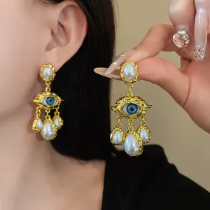 Detailed view of vintage gold-tone evil eye earrings featuring elegant dangling white pearls