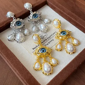 Detail of vintage evil eye pearl drop earrings in gold and silver tones for women