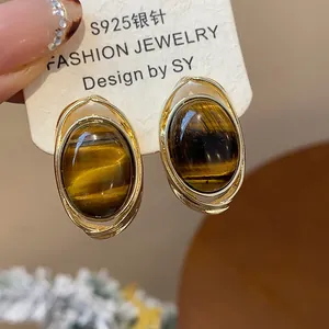 Detail of vintage oval brown resin earrings with gold plating and silver posts on display card