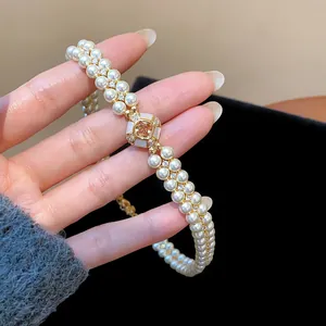 Elegant detail of 18k gold-plated double-row pearl bracelet with a central zircon stone