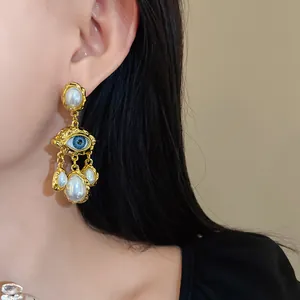 Exquisite vintage gold evil eye earrings with teardrop faux pearls shown on a model's ear