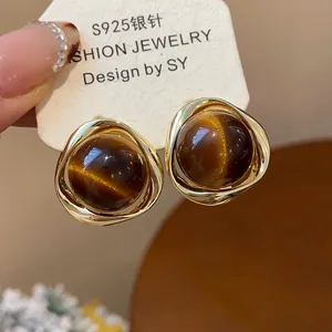 Detail of gold-plated silver needle earrings with Maillard brown resin cat-eye beads