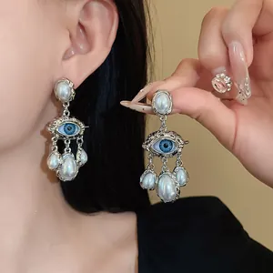 Close-up macro detail of vintage silver needle eye earrings with dangling faux pearls