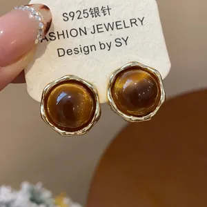 Close-up detail of amber resin stud earrings featuring gold-plated frames and S925 silver posts