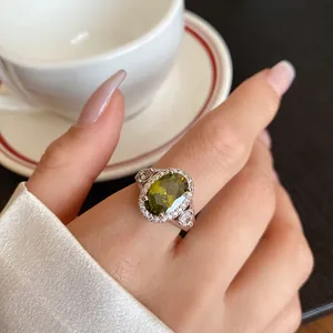 Primo piano di un anello in argento con grande pietra preziosa ovale verde al dito