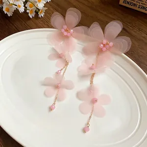 Eleganti orecchini a nappa con fiori in chiffon rosa e perle di vetro su piatto bianco.