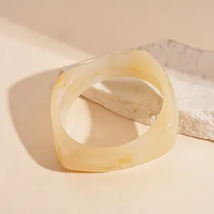 Close-up detail shot of a vintage irregular resin bangle with soft marbled amber pattern
