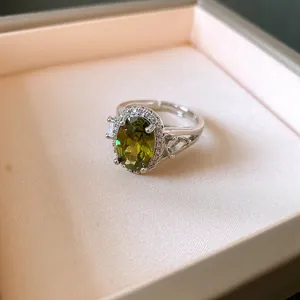Primo piano di un anello regolabile argento con gemma ovale verde oliva e zirconi lucenti