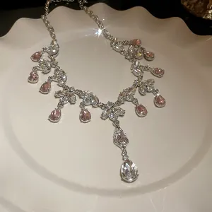 Détail du collier pampille en cristal feuille et goutte rose sur un plateau élégant.