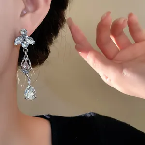 Détail rapproché d'élégantes boucles d'oreilles feuille argentée avec pompons en strass