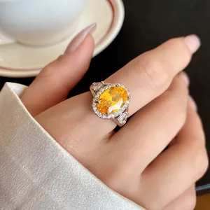 Primo piano di un elegante anello in argento con una grande pietra gialla ovale sulla mano