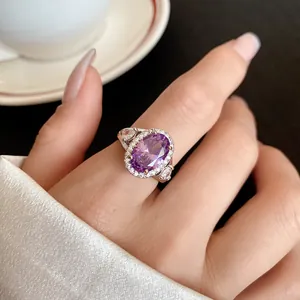 Dettaglio di un elegante anello argentato con pietra viola ovale e alone di zirconi.