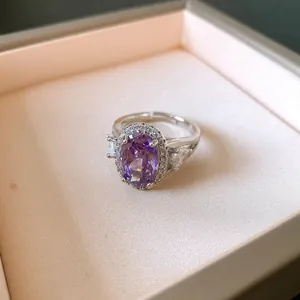 Dettaglio macro di un elegante anello in argento con zircone viola ovale e cornice di pietre.