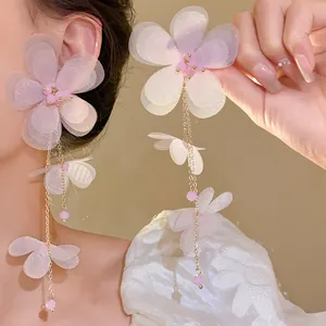 Dettaglio che mostra la texture degli orecchini con nappa in chiffon rosa indossati
