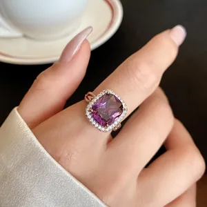 Primo piano di un anello d'argento con un grande zircone viola a cuscino e pietre halo.
