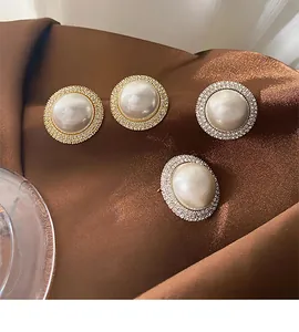 Close-up of luxury pearl earrings with micro-pave crystal borders on brown fabric
