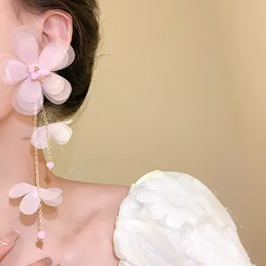 Dettaglio di eleganti orecchini a nappa con fiori di chiffon rosa e catene d'oro