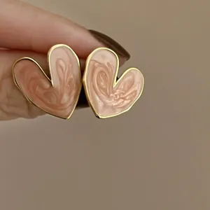 Macro view of elegant heart-shaped earrings with pink enamel finish and gold edges