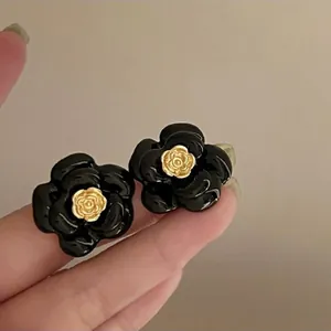 Detailed close-up view of elegant black camellia flower stud earrings with gold rose center