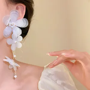 Dettaglio di orecchini a nappa con fiori in chiffon bianco indossati