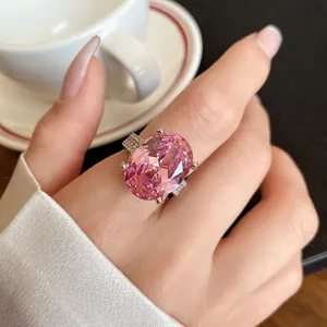 Dettaglio di un lussuoso anello regolabile con zircone rosa ovale su una mano con caffè