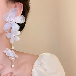 Dettaglio di eleganti orecchini a nappa con fiori in chiffon bianco su orecchio