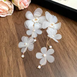 Primo piano di orecchini a nappa con fiori in chiffon bianco e catene dorate
