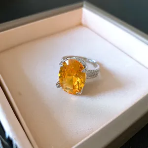 Dettaglio di un anello argentato con grande zircone arancione ovale in scatola