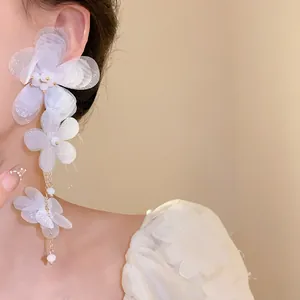 Dettaglio del fiore di chiffon bianco a strati e della nappa delicata sull'orecchino.