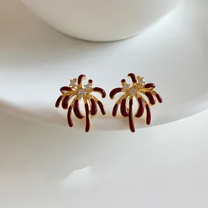 Macro view of elegant 18k gold plated firework stud earrings with red enamel and zircons