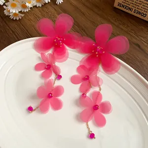Dettaglio di lunghi orecchini nappa con fiori in chiffon rosa e perle di vetro fini