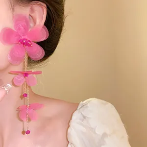 Dettaglio ravvicinato dell'orecchino con fiore di chiffon rosa a strati e nappa lunga elegante