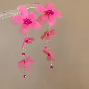 Dettaglio di orecchini a nappa con fiori in chiffon rosa e perle di vetro eleganti