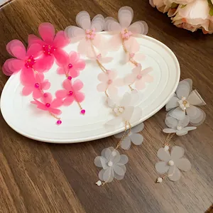 Vista dettagliata di orecchini a nappa con fiori in chiffon fatti a mano su piatto bianco