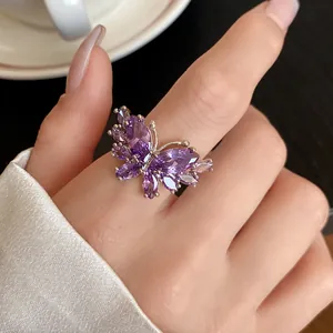 Dettaglio di un elegante anello a farfalla in zircone viola sulla mano di una modella