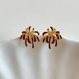 Detailed view of firework stud earrings with red enamel and sparkling zircons in gold plating.