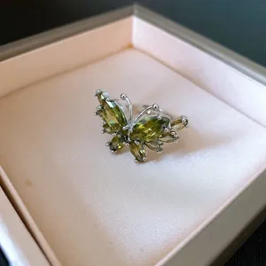 Primo piano di un anello a farfalla in argento con zirconi verdi brillanti e rifiniti
