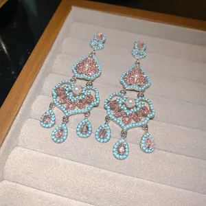 Détail de boucles d'oreilles évidées de style palais avec cristaux roses et perles argent