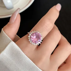 Primo piano di un anello in argento con un grande zircone rosa rotondo e alone bianco al dito.