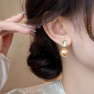 Close-up view of elegant French vintage pearl drop earrings with gold finish on model ear