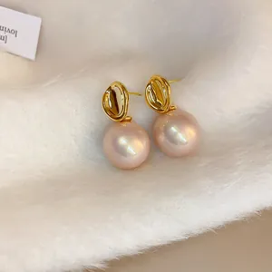 Detailed macro view of French retro gold earrings with large pink pearls on soft white fur