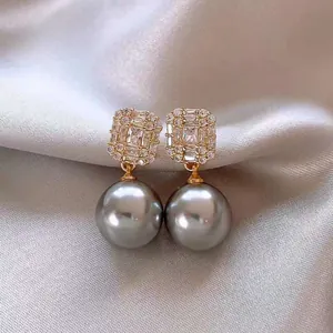 Close-up of elegant French vintage grey pearl earrings with sparkling rectangular studs.