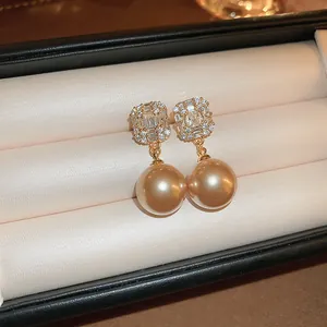 Detailed close-up view of elegant golden pearl drop earrings with sparkling stone studs