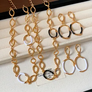 Detailed view of gold-tone oval link necklace and enamel earrings in black and white