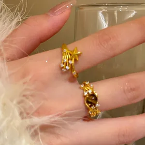 Close-up view of elegant 18k gold plated star and tiger eye rings on a woman's hand
