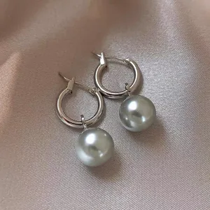 Close-up of French retro silver hoop earrings with elegant grey pearl drops on silk.