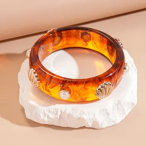 Vintage amber resin bangle bracelet featuring gold shell accents and white faux pearls