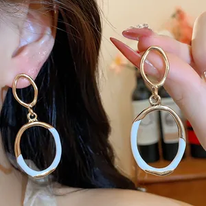 Close-up of elegant oval court-style earrings with white and gold oil-drop finish