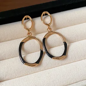 Close-up of black enamel and gold oval drop earrings in a luxury jewelry box display