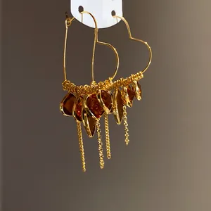Detail view of 18K gold plated heart earrings with amber teardrop tassels and stones
